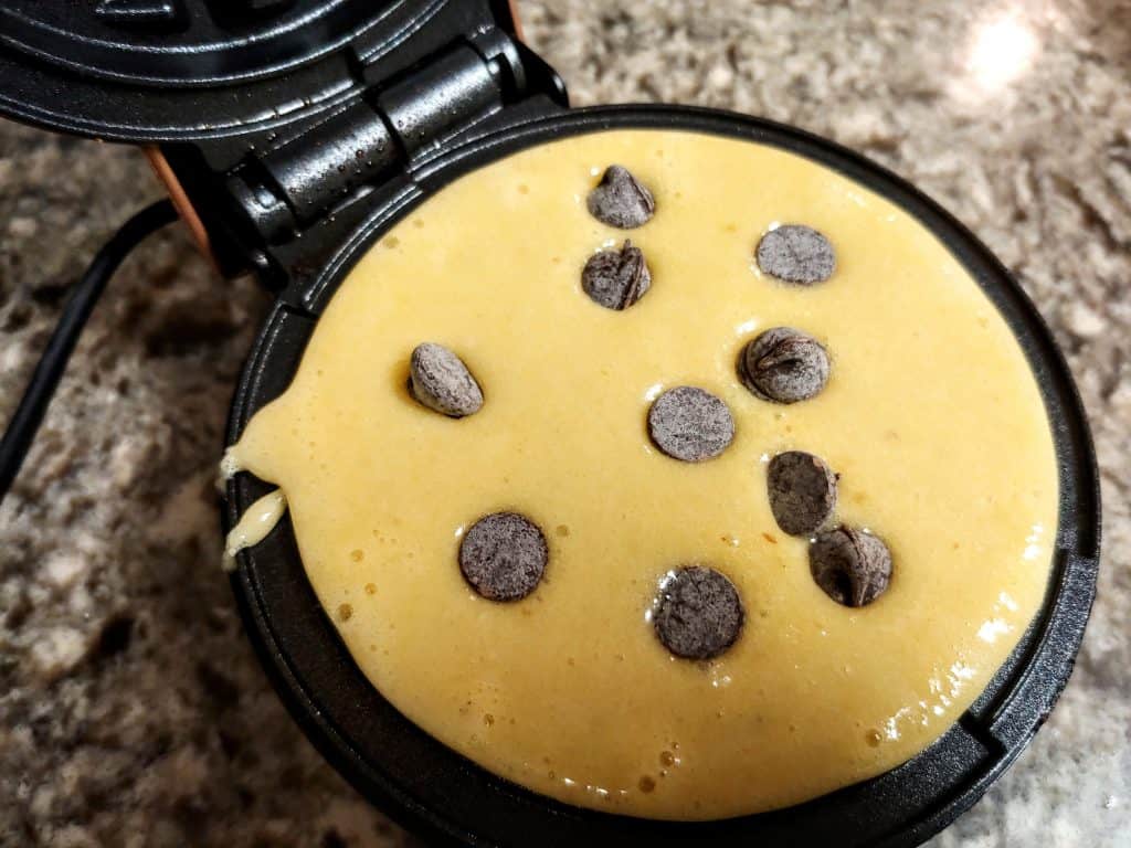 Gluten Free Waffle Batter in a Dash Mini Waffle Maker Sprinkled with Chocolate Chips